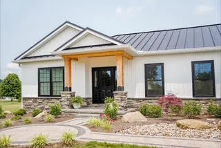Modern white farmhouse with black replacement windows and a standing-seam metal roof